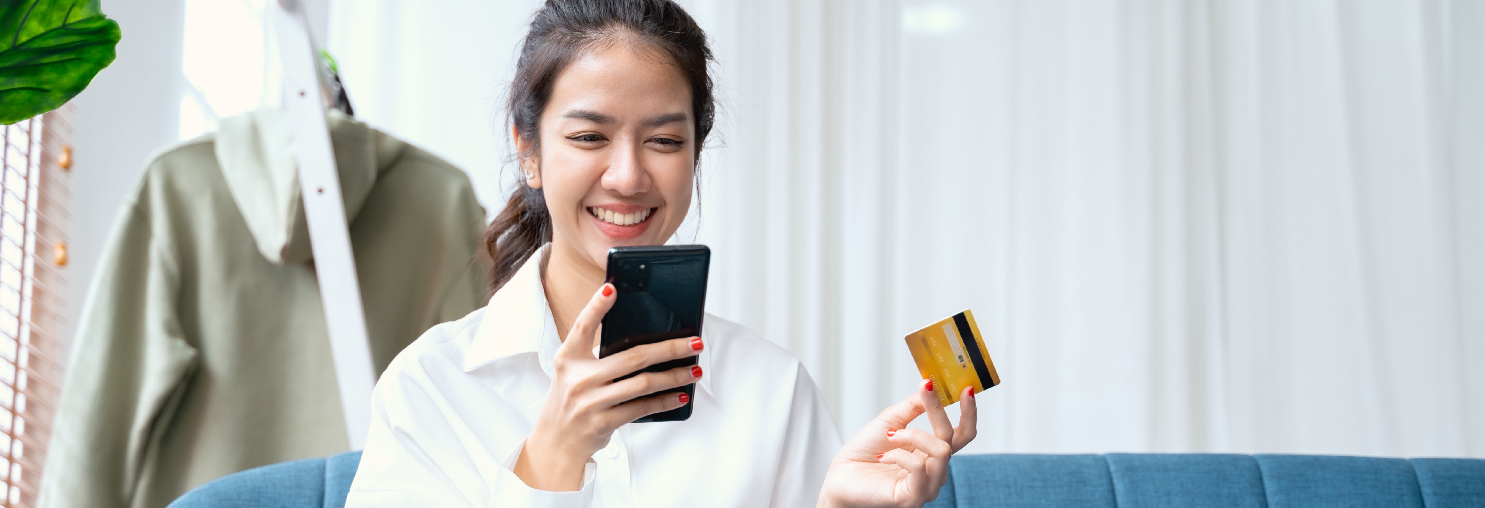 Woman holding debit card and cell phone