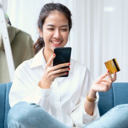 Woman holding debit card and cell phone